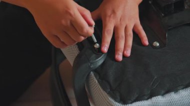 Sandalyeyi monte etmek için bir tornavida kullanan yakın plan eller. Konferansta mobilya montajının ayrıntılı çalışmaları, zanaatkarlık ve ayrıntılara dikkat edilmesi üzerinde duruluyor..
