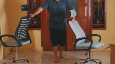 Ahşap kapılı, aydınlık bir odada modern ergonomik ofis sandalyesini ayarlayan bir kişi. Sandalye, rahat ve stili vurgulayan bir ağ arkası ve ayarlanabilir başlık içerir..