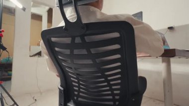 Modern ergonomik ofis sandalyesi, çalışma alanı ortamında konumlanmış ağ gergisi. Sandalye arkadan gösteriliyor, tasarım ve konfor özelliklerini vurguluyor.