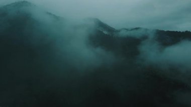 Sisli dağların sisle kaplı havadan görünüşü gizemli ve atmosferik bir manzara yaratıyor. Sahne bir sükunet ve yalnızlık hissi uyandırıyor..