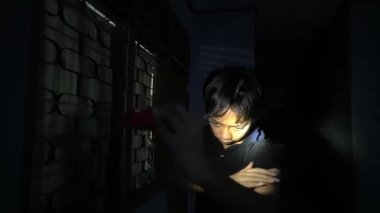 Geceleri pencereden içeri bakmak için el feneri kullanan biri dramatik ve şüpheli bir atmosfer yaratıyor. Gölgeler ve ışık, kişinin odaklanmış ifadesini vurgular..