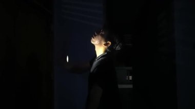 Loş bir odada el feneriyle aydınlatılmış bir insan. Gölgeler dramatik bir atmosfer yaratarak gizemli atmosferi güçlendirir. Bireyler dalgın görünür, sahnenin entrikalarına eklenir..