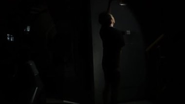 Siyah giysili, dramatik bir poz veren birinin olduğu loş bir oda. Arka plan çoğunlukla karanlık, gizemli bir atmosfer yaratıyor. Şekil uzanıyor gibi görünüyor, bir hareket ve duygu hissi ekliyor..