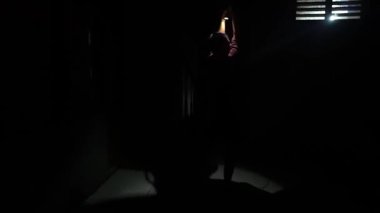 Karanlık bir ortamda, küçük bir ışık kaynağıyla aydınlatılmış gizemli ve dramatik bir atmosfer yaratan bir çocuk. Çocuk el hareketi yapıyor ya da oynuyor gibi görünüyor..