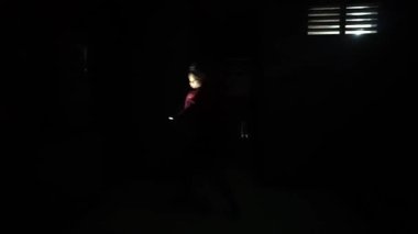 Karanlık bir odada elinde fener tutan birinin silüeti yerde uzun bir gölge bırakıyor. Atmosfer esrarengiz ve belirsizdir. Minimum ışık çevreyi aydınlatır..