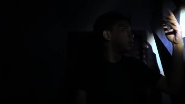 Loş bir alanda duran bir insan, alanı aydınlatmak için el feneri kullanıyor. Işık, karanlık çevreye karşı dramatik bir zıtlık yaratır. Bu da gizem ya da belirsizlik hissi verir..