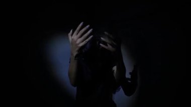 Yumuşak bir ışık kaynağı tarafından aydınlatılmış, başka tarafa bakan bir kişinin silüeti. Arka plan karanlık, gizemli bir atmosfer yaratıyor..