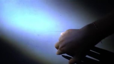 Duvara doğru uzanan, yumuşak bir ışıkla aydınlatılan, dramatik bir gölge bırakan bir elin yakın çekimi. Odak noktası elin narin parmakları ve duvarın dokusu..