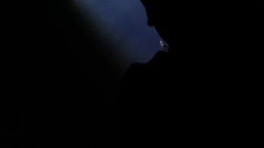 Siluetli eller karanlık bir ortamda bir ışık kaynağına uzanıyor, çarpıcı bir kontrastlık ve ruhani bir atmosfer yaratıyor..