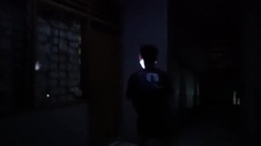 Karanlık bir odada, pencereden gelen soluk bir ışıkla aydınlanan bir kişinin silüeti. Atmosfer esrarengiz ve ürkütücü. Gölgeler dramatik bir etki yaratıyor..