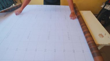 Tahta desenli büyük bir yaprak tutan bir insan zengin kahverengi tonlarını ve dokusunu sergiliyor. Arka planda bir masa ve bir motosiklet görüntüsü olan basit bir ayar var..