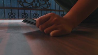 Ahşap bir yüzeye kaplama uygulayan bir kişi, ustalık ve detaylara dikkat gösteriyor. Arka planda dekoratif bir korkuluk var. Olay yerine derinlik katıyor..