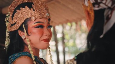 Süslü altın başlıklı ve geleneksel makyajlı güzel bir Cava kadını. Partnerine bakıp güler ve gülümser. Saf neşe, sevgi ve şefkat ifade eder..