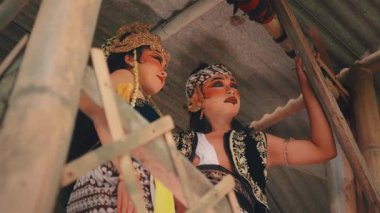 Geleneksel kostümlü bir Javalı çiftin kırsal bir kulübede şakacı ve romantik bir şekilde etkileşime girdiği düşük açılı bir çekim. Bu tiyatro sahnesi hikaye anlatmayı, aşkı ve kültürel performansı çağrıştırıyor..