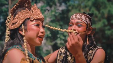 Geleneksel Cava kıyafetleri içinde mutlu bir Endonezyalı çiftin yakın çekimi. Kadının burnuna yasemin çiçeği dizip büyüleyici ve romantik bir an yaratan adamla neşe içinde gülüp etkileşime geçiyorlar..