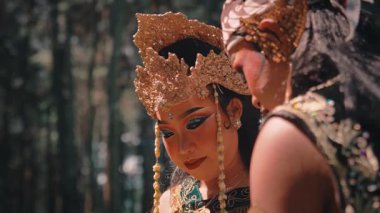 Geleneksel giyinmiş bir Java çifti ormanda mutlu ve samimi bir anı paylaşıyor. Gülümserler, gülerler, el ele tutuşurlar, derin bağlarını ve neşelerini gösterirler..