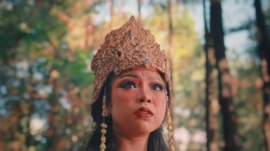 Şok olmuş ya da korkmuş bir ifadeyle kadın bir Cava sanatçısının dramatik yakın plan portresi. Gösterişli kostümü, altın başlığı ve tiyatro makyajı bu duygusal performansta vurgulandı..