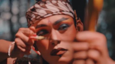 Dramatik makyajlı ve okla ok ve yay doğrultmuş bir Cava okçusunun yoğun yakın çekimi. Endonezya folklorundan güçlü bir savaşçıyı canlandıran kararlı ifadesine odaklanmış durumda..