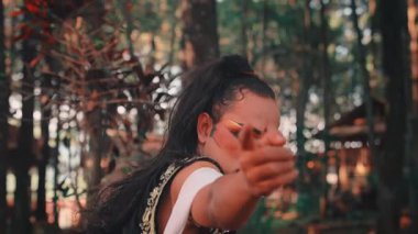 Dramatik makyajlı ve geleneksel Cava kostümlü bir adam kameraya yoğun bir şekilde bakar ve ileriye bakar. Bir ormanda güçlü, çekici ve çatışmacı bir portre oluşturur..