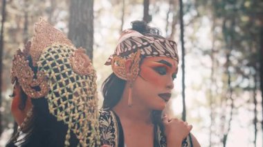 İki geleneksel Java dansçısının yakın çekimi. Cesur makyajlı bir erkek dansçı hüzünlü bir anı ya da klasik bir hikayeden derin bir düşünceyi yansıtan kasvetli bir ifadeyle aşağıya bakar..