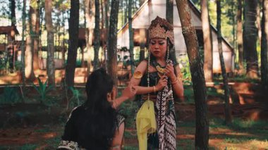 Dramatik bir açık hava sahnesi. Geleneksel kostümlü ayakta duran bir Java dansçısı diz çöken ortağına arkasını döner. Bir anlık üzüntü, çatışma ya da klasik bir hikayeden ayrılışını betimler..