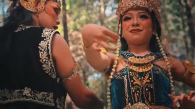 Güzel bir Java dansçısının partneriyle büyüleyici bir yakın çekimi. Anlamlı yüzü, karmaşık makyajı ve ellerinin zarif hareketi geleneksel Endonezya folklorundan bir hikaye anlatıyor..