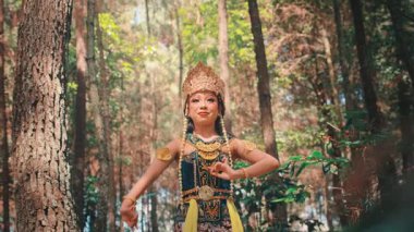 Altın bir başlık takmış güzel bir Cava 'lı kadın kutsal ve zarif bir dans sergiliyor. Kamera onun sakin bir orman zeminine karşı sakin ifadesini yakalamak için içeri giriyor..