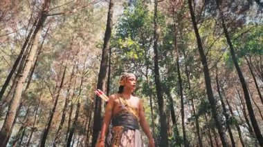 Mitolojiden kahraman bir okçuyu canlandıran Cava 'lı bir erkek dansçı, elinde altın bir yay, gücü, geleneği ve Endonezya folklorunu temsil eden güneşli bir çam ormanında yürür..