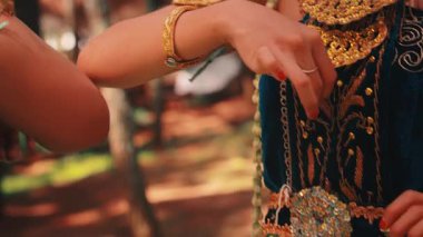 İki geleneksel Cava dansçısının senkronize kol ve el hareketlerine odaklanan yakın çekim. Süslü kostümlerinin, altın bileziklerinin ve zarif jestlerinin ayrıntıları görünür..