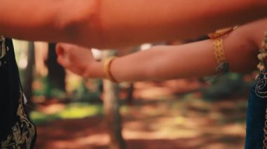 Sanatsal bir yakın plan, iki Java dansçısının ormanda birlikte yaptıkları akıcı ve zarif el hareketlerini yakalıyor. Süslü kostümlerini ve altın mücevherlerini vurguluyorlar..