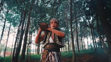 Geleneksel giysiler içinde güçlü bir Cava erkek dansçısı ormanda güçlü, ritüel bir dans yapar, ağır bir taşı kaldırır ve dramatik bir yoğunlukla yere çarpar..