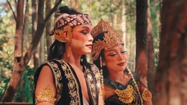 Geleneksel kostümlü ve makyajlı bir kadın ve erkek Cava dansçısı şefkatli bir kucaklaşmayı paylaşıyor. Kadın başını omzuna dayayıp Endonezya folklorundan romantik bir sahneyi canlandırıyor..