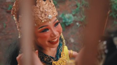 Bambu bir yapının çatallarından neşeli bir Java çifti gösteren yaratıcı bir çekim. Gülüyorlar ve samimi bir şekilde etkileşime geçiyorlar. Özel ve mutlu bir anı izliyorlar..