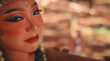 Kadın bir Cava dansçısının profilinin yakın plan çekimiyle, uzaktaki erkek partneri arasında derin ve duygusal bir bağ kuran sinematik bir çekim odağı..