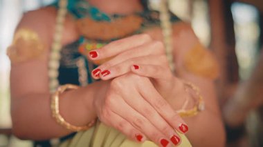 Dişi bir Cava dansçısının hassas ve anlamlı ellerine odaklanan yakın plan bir çekim. Kırmızı boyalı tırnakları ve altın bilezikleri zarif ve geleneksel hareketleri vurguluyor..