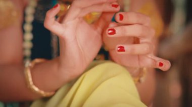 Dişi bir Cava dansçısının hassas ve anlamlı ellerine odaklanan yakın plan bir çekim. Kırmızı boyalı tırnakları ve altın bilezikleri Mudra olarak bilinen zarif ve geleneksel hareketleri vurguluyor..