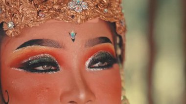 Kadın bir Cava dansçısının göz ve alnının makro detaylı bir fotoğrafı. Geleneksel makyajı, takma kirpikleri ve göz kamaştırıcı detaylarla süslenmiş altın başlığı gösteriyor..