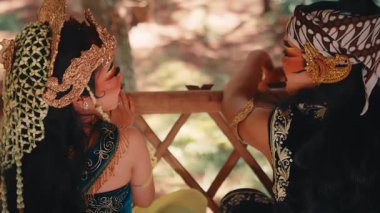 Arkadan çekilen sinematik bir Cava çifti. Ormana tepeden bakıyor. Odak noktaları parmaklıklar ve uzak ağaçlar arasında kayar. Birbirleriyle ve doğayla olan bağlantılarını vurgularlar..