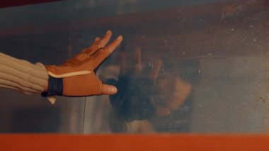 Kirli bir cam yüzeyden görülebilen, silah tutan birinin bulanık yansıması. Görüntü bir gerilim ve gizem hissi veriyor..