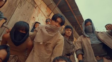 Kıyametten sonraki engebeli, katmanlı giysiler ve maskeler giyen bir grup birey. Yakından toplanırlar, dayanıklılık ve dayanıklılık hissi yayarlar..