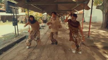 İki dansçı açık havada, kırsal ve endüstriyel bir zeminde gösteri yapıyorlar. Sahne hareketlerini ve enerjilerini yakalıyor, şık kıyafetlerini ve dinamik pozlarını sergiliyor..