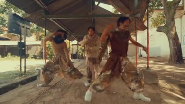 Kırsal mimariyle açık havada dinamik bir dans hareketi yapan bir kişi. Sahne, yeşil ve eski yapılarla çevrili hareket ve enerjiyi yakalıyor..