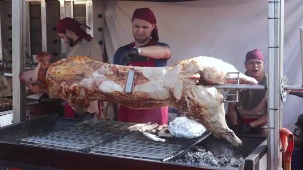 シェフはスペインのTorreeviejaの地元の食品市場で串焼きに豚の肉を切る一方 別の料理人はあくびをしています — ストック動画
