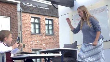 Genç bayan öğretmen el pençe divan oturuyor çünkü çocuk, Antwerp 'teki yerel bir fuarda cep telefonuyla ağır çekim videosunda.