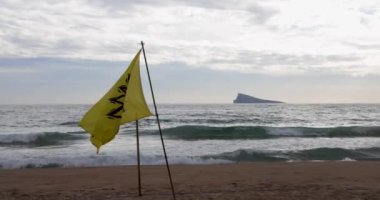 Sarı Benidorm SOS uyarı bayrağı popüler İspanyol turist kasabasındaki plajda dalgalanırken asılıydı. Yavaş çekim videosu