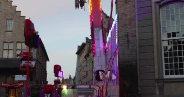 People having fun and enjoying ride at fair attraction during evening in slow motion footage