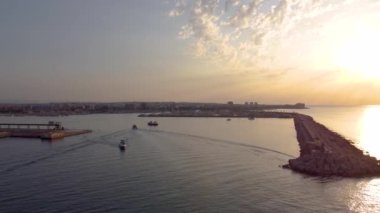 Güneş doğarken Torrevieja limanındaki deniz fenerinin etrafındaki 4K 'lık insansız hava aracı videosu marinaya geliyor.