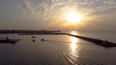 Güneş doğarken Torrevieja limanındaki deniz fenerinde tekneler marinaya gelirken insansız hava aracı görüntüsü.