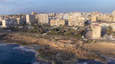 İspanya 'nın Torrevieja kentindeki Cabo Cervera' da kayalık plajların ve dairelerin insansız hava görüntüsü.