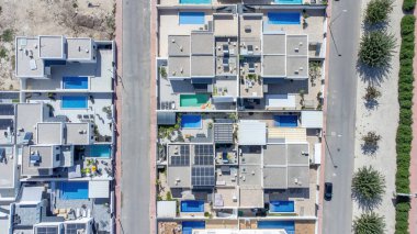 Aerial top down view of a modern residential complex in Daya Nueva, Spain, featuring homes with pools, solar panels, and landscaped patios. clipart